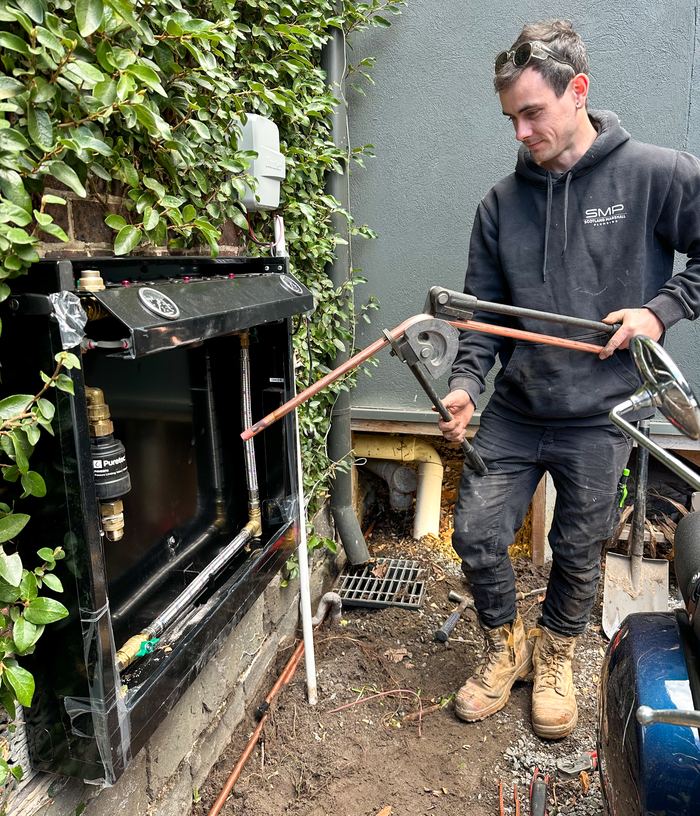 SMP plumber bending copper pipe to connect a Puretec FilterWall