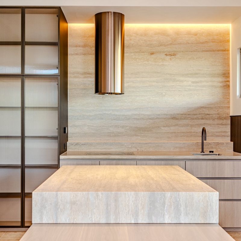 Kitchen with travertine benchtop and island in a South Melbourne home plumbed by Scotland Marshall Plumbing